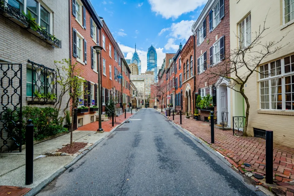 Street with old buildings in Philadelphia, Pennsylvania and modern high-rise buildings in background.